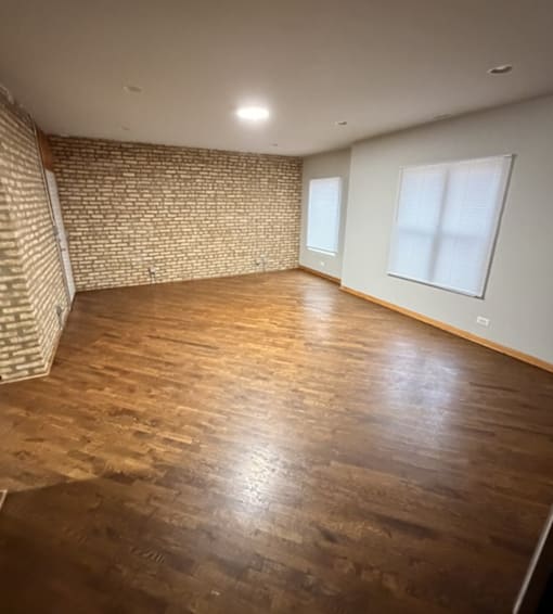 A room with wooden flooring and a brick wall.