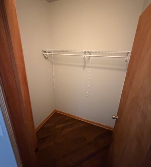 A white coat rack with four hooks is mounted on a white wall.