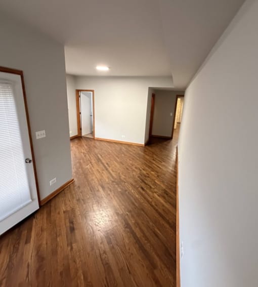 A long hallway with wood floors and white walls.