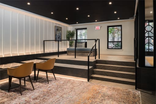 the lobby of a building with tables and chairs and a staircase