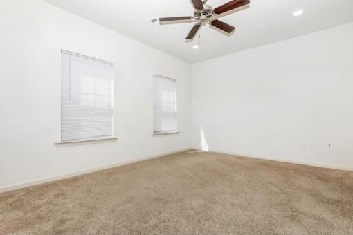 an empty living room with a ceiling fan and a window