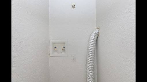 A white wall with a socket and a white hose.