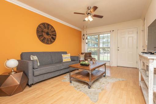 A living room with a grey couch, a wooden coffee table, and a ceiling fan. at The Cove at State Street Apartments, Louisiana, 70802