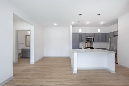 A kitchen with a white island and wooden floors.