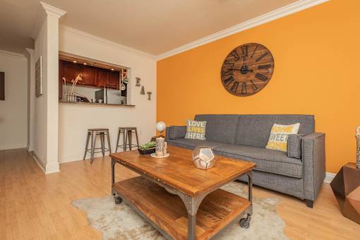 A living room with a grey couch and a wooden coffee table. at The Cove at State Street Apartments, Baton Rouge