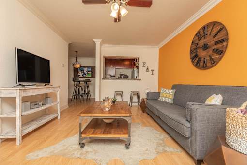 A living room with a grey couch, a wooden coffee table, and a flat screen TV. at The Cove at State Street Apartments, Baton Rouge, LA