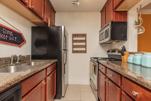 A kitchen with a black fridge and wooden cabinets. at The Cove at State Street Apartments, Baton Rouge, LA