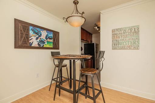 A dining room with a table and chairs and a painting on the wall. at The Cove at State Street Apartments, Baton Rouge