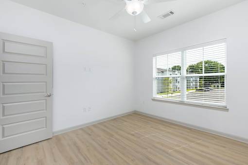 A room with a white door and a window with blinds.