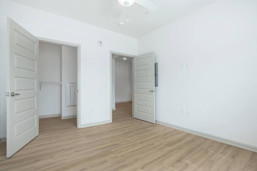 A room with three doors and a wooden floor.