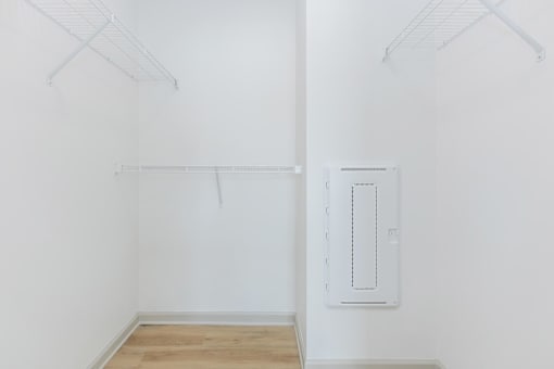 A white wall with a white door and a white shelf.