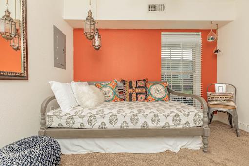A bedroom with a bed, a chair, and a mirror. at The Cove at State Street Apartments, Baton Rouge, LA, 70802
