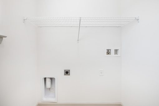 A white bathroom with a toilet paper dispenser on the wall.