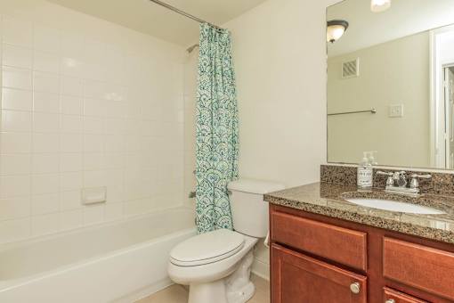 A white toilet sits next to a bathtub in a bathroom. at The Cove at State Street Apartments, Louisiana
