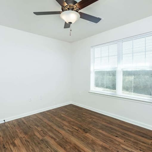 an empty room with a ceiling fan and a window