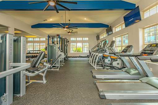 A gym with treadmills, exercise bikes, and a fan. at The Cove at State Street Apartments, Baton Rouge, LA, 70802