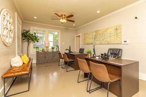 A room with a brown desk and chairs, a ceiling fan, and a map on the wall. at The Cove at State Street Apartments, Baton Rouge