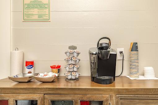 A coffee maker is on a wooden counter with a sign above it. at The Cove at State Street Apartments, Baton Rouge, Louisiana