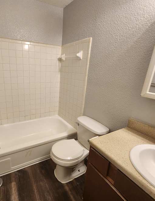 A white toilet sits next to a bathtub in a bathroom.