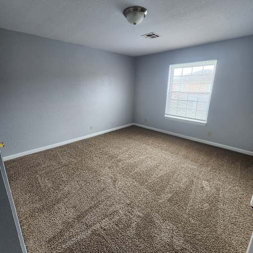 A room with a carpeted floor and a window.
