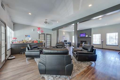 A living room with black leather furniture and a flat screen TV.