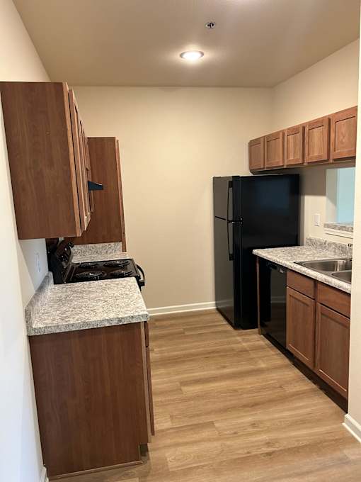 A kitchen with a black refrigerator and wooden cabinets.