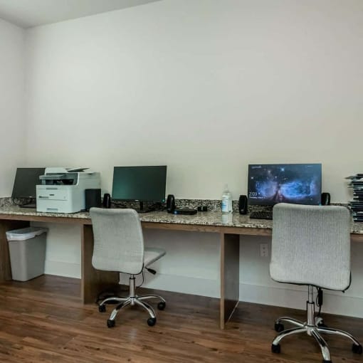 two desks with two computers and a printer in an office