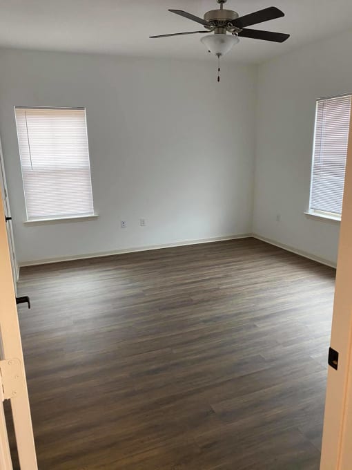an empty room with wooden floors and a ceiling fan