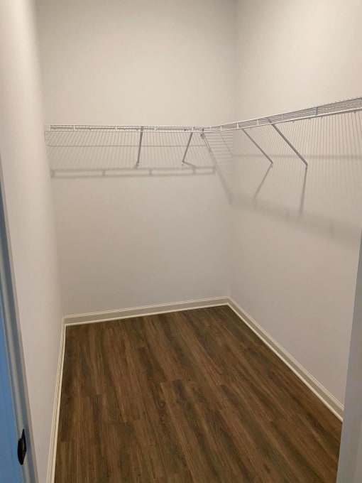 a room with white shelves on the wall and wooden floors