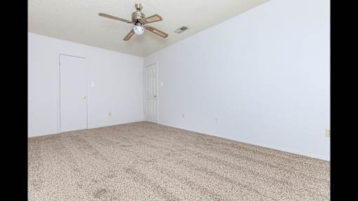 A room with a ceiling fan and carpeted floor.