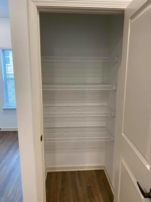 a walk in closet with white shelves and a door