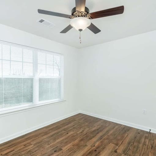an empty room with a ceiling fan and a window