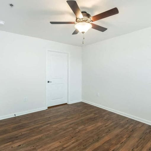 an empty room with a ceiling fan and a door