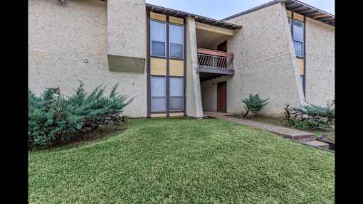 A building with a balcony and a green lawn in front.