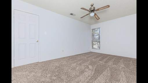 A room with a ceiling fan and carpeted floor.