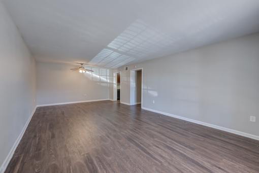 A room with a ceiling fan and light, and a door leading to another room.
