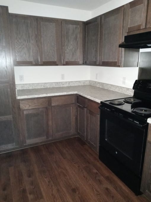 a kitchen with wooden cabinets and a stove and a black stove