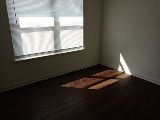 an empty room with a window and wooden floors