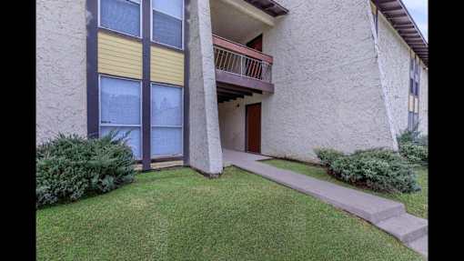 A building with a balcony and a small garden in front.