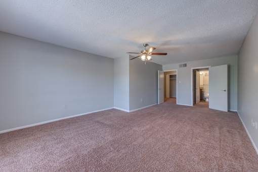 Empty room with a ceiling fan and carpeted floor.