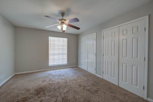 A room with a ceiling fan and carpeted floor.