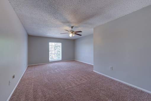 A room with a ceiling fan and a window.