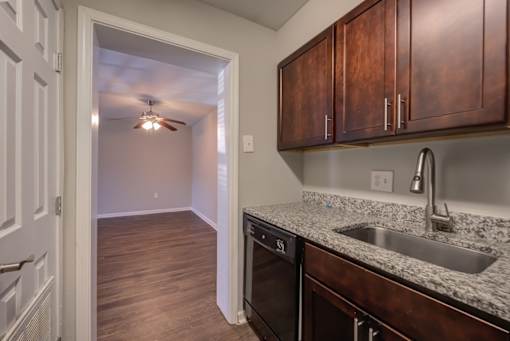 A kitchen with a sink, stove, and cabinets.