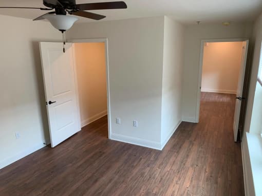 a bedroom with wood flooring and a closet and a ceiling fan