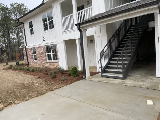 the front of a house with a concrete driveway and stairs