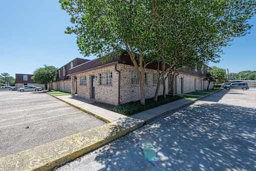 A parking lot with a building and a tree in front.