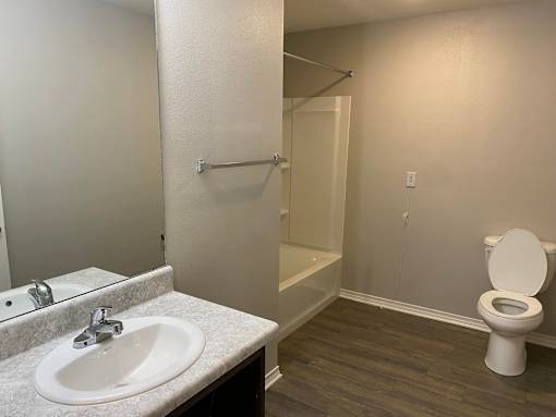 A bathroom with a toilet, sink, and mirror.