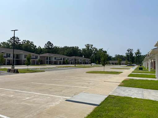 A parking lot with a few cars and a building in the background.