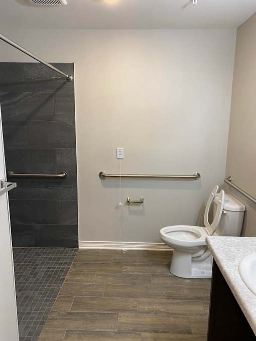 A white toilet sits in a bathroom next to a shower.