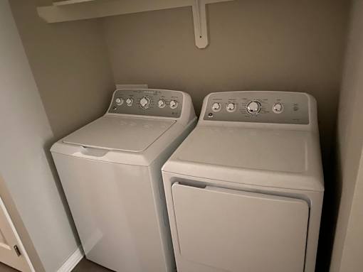 Two white front loading washing machines in a small laundry room.
